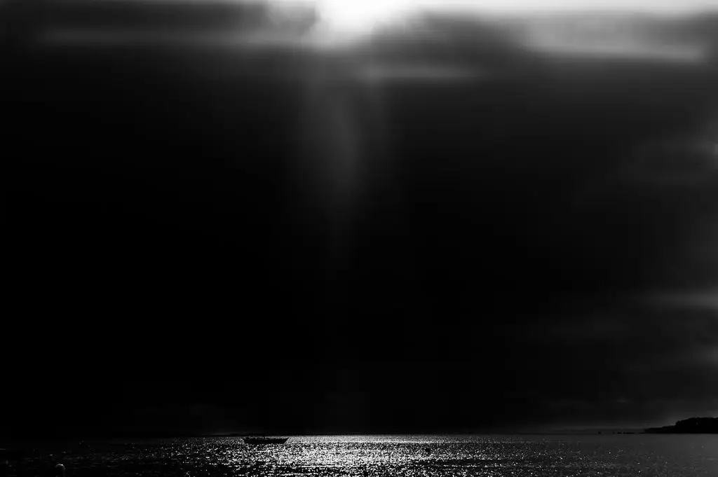 Rayon de lumière perçant un ciel sombre et éclairant un seul point du Bassin, en noir et blanc