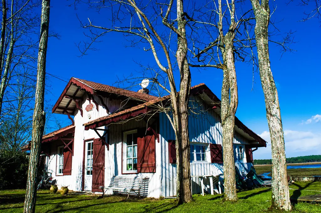 La villa Podensac, ancienne gare de la voie Decauville devenue maison de famille, en bois blanche aux volets rouges, sous les arbres
